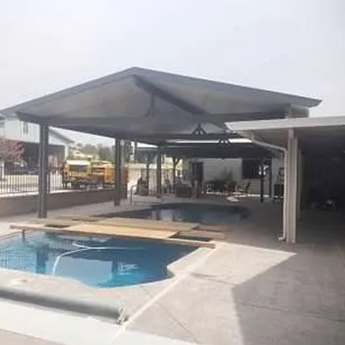 There is a swimming pool in the backyard with a canopy over it.