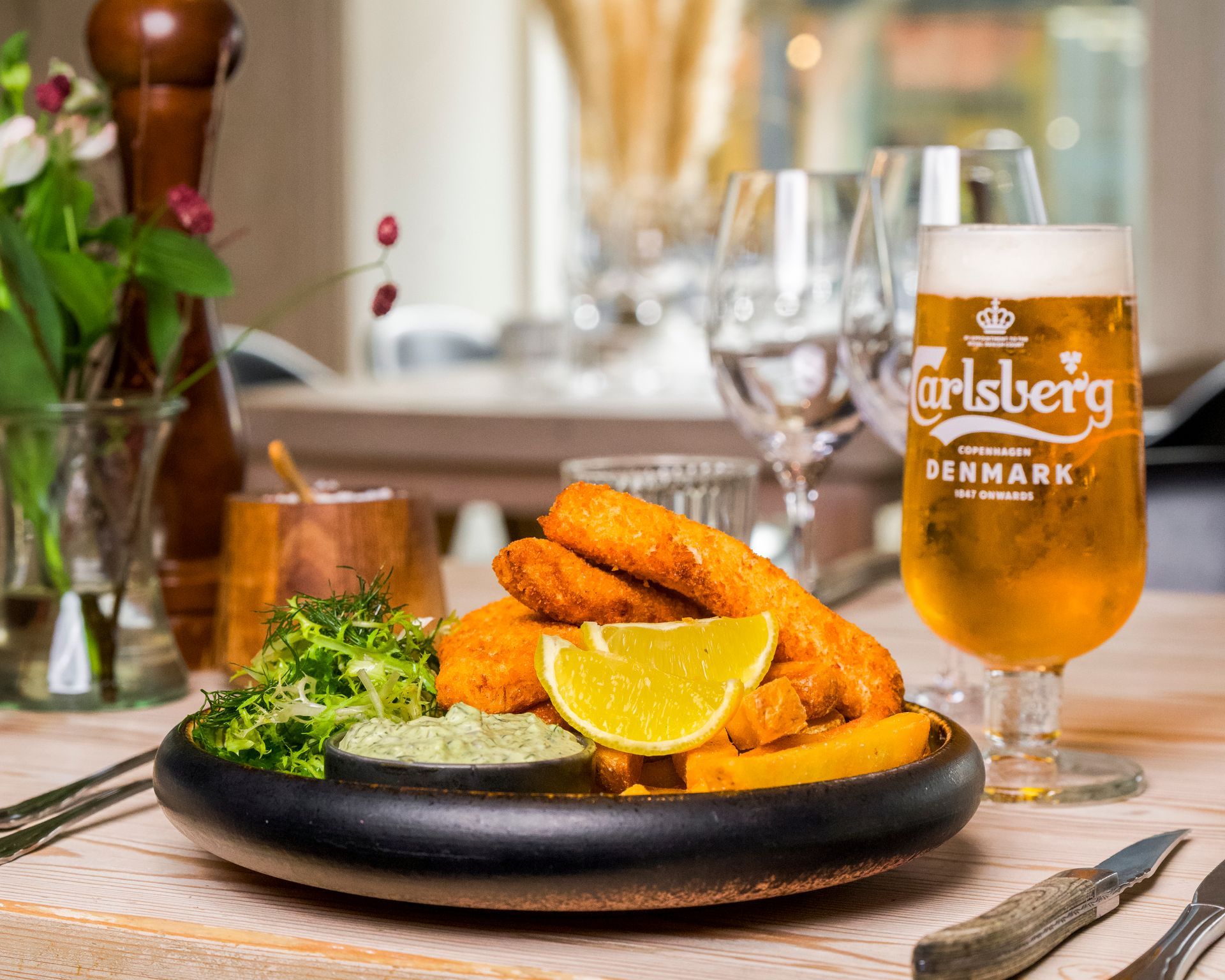 Fish and chips med øl i restaurantomgivelser.