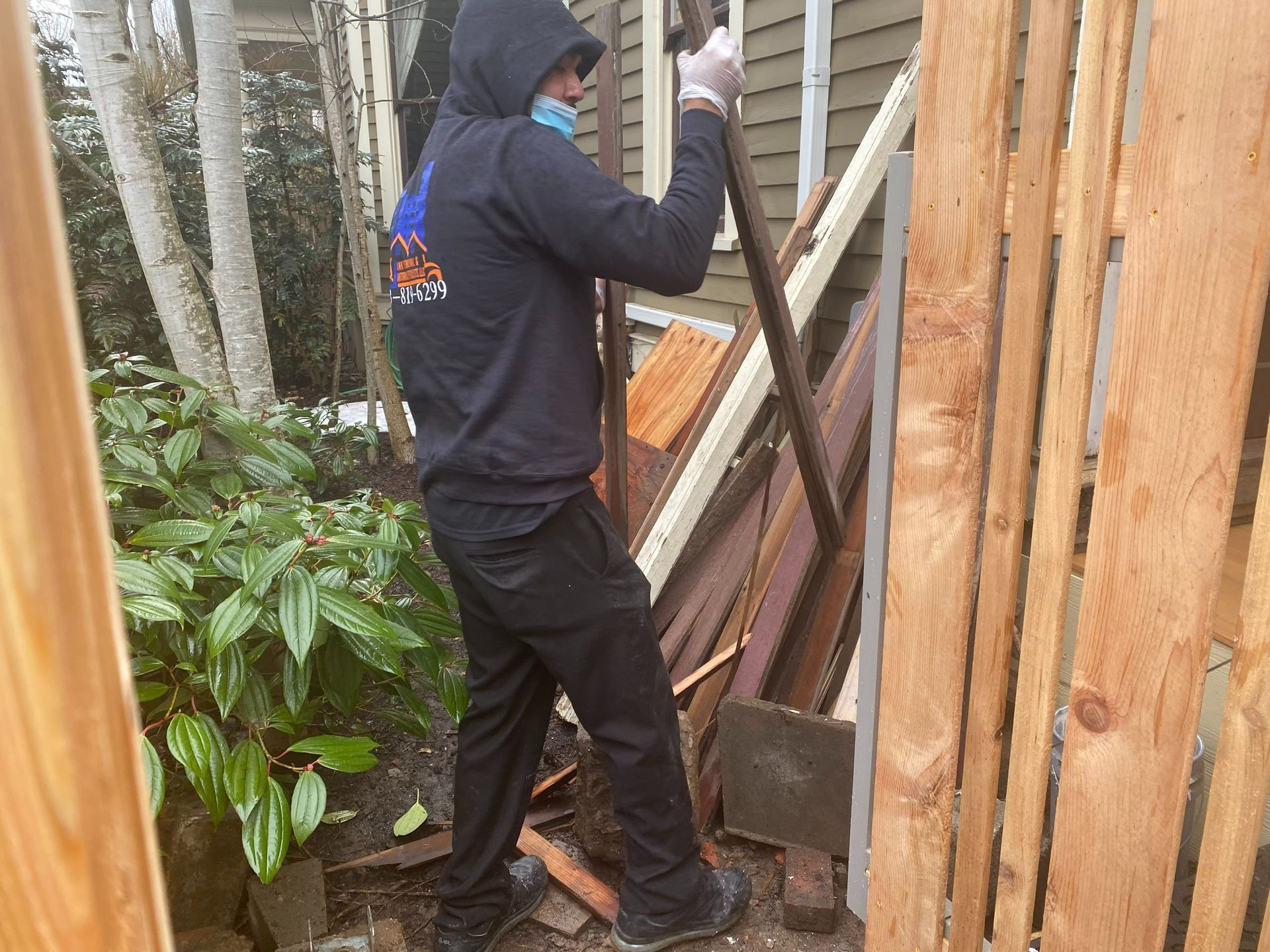 Person wearing a mask and gloves, working with wood debris.