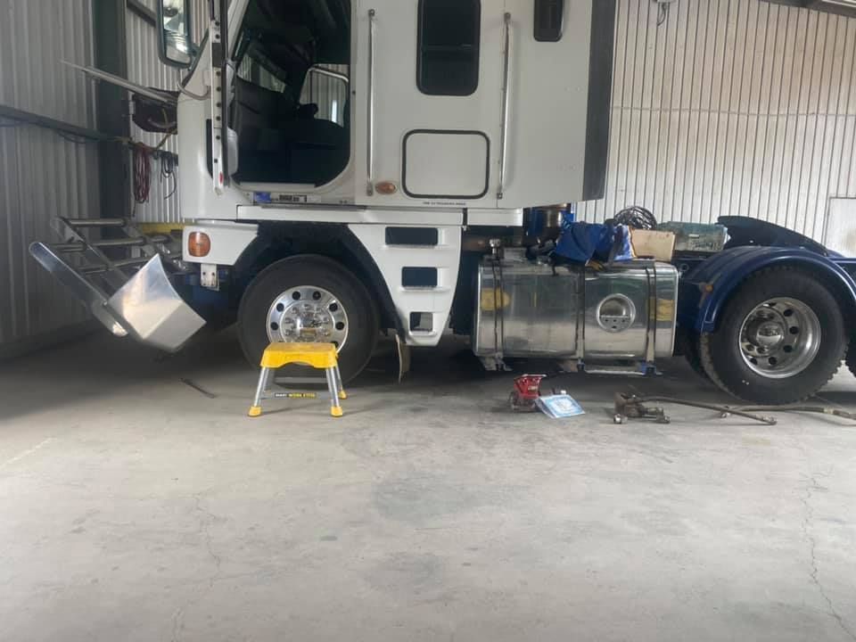 A white semi truck is parked in a garage next to a yellow ladder. — Gillies Enterprises Pty Ltd In Narrabri, NSW