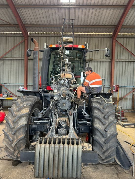 A Man Is Working On A Tractor In A Garage — Gillies Enterprises Pty Ltd In Narrabri, NSW