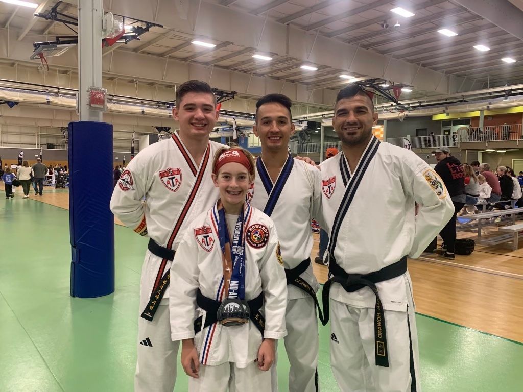A group of people in martial arts uniforms are posing for a picture in a gym.