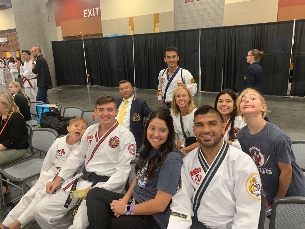 A group of people in martial arts uniforms are sitting in chairs.