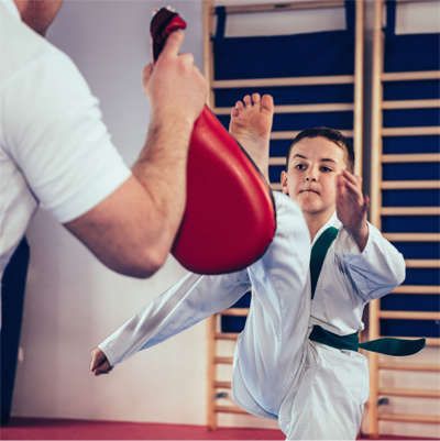 a young boy is practicing karate with a red kick pad .
