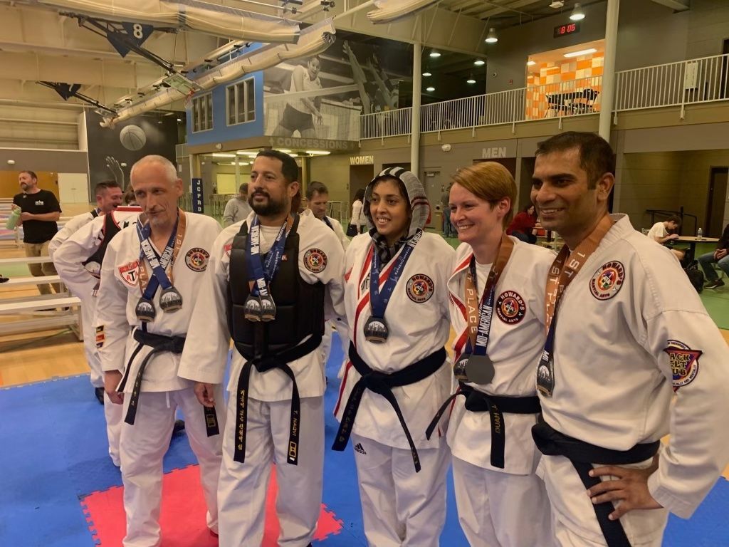 A group of people wearing karate uniforms and medals are posing for a picture.