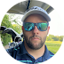 a man wearing sunglasses and a hat is standing in a golf cart .