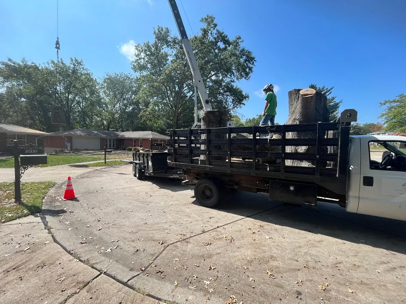A white truck is parked in a driveway next to a crane.
