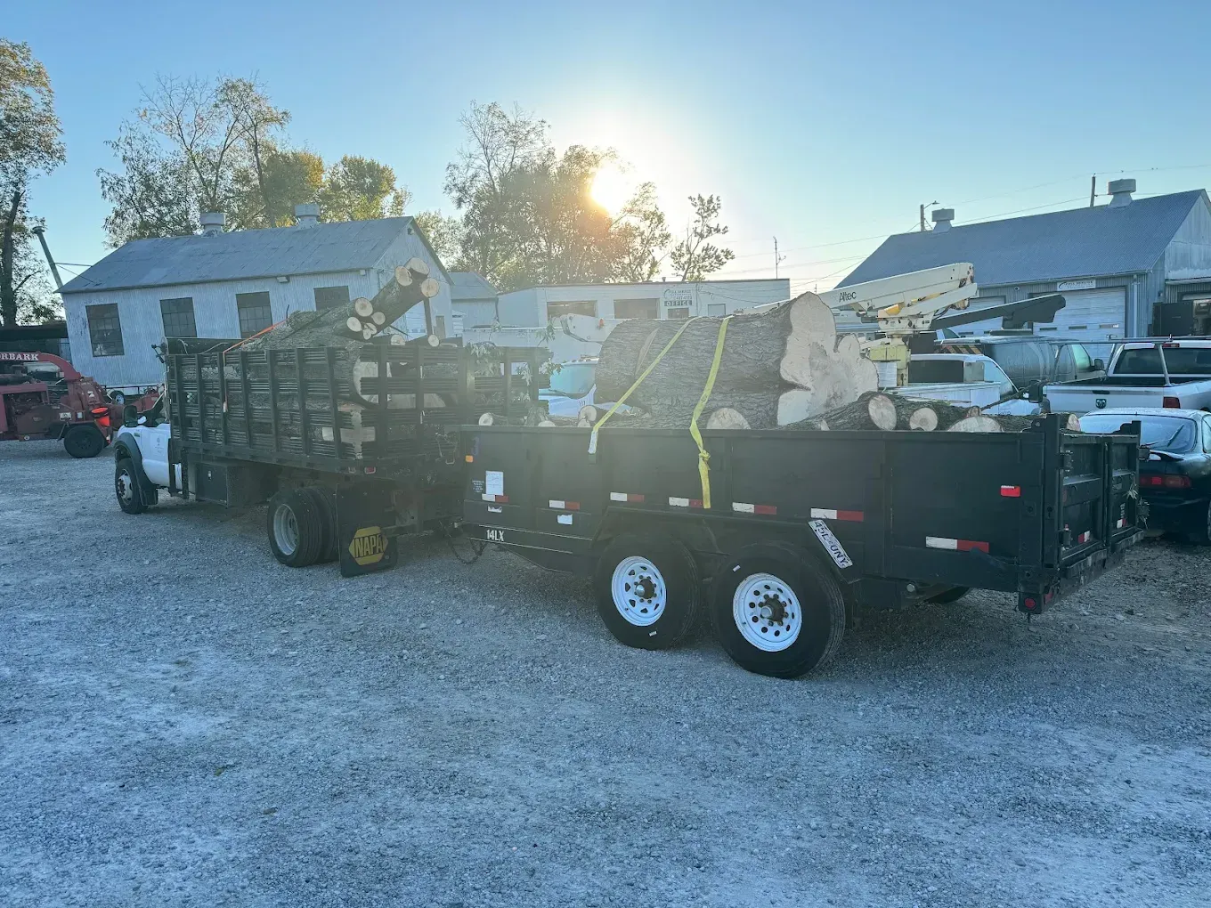 A dump truck is pulling a trailer full of junk in a parking lot.