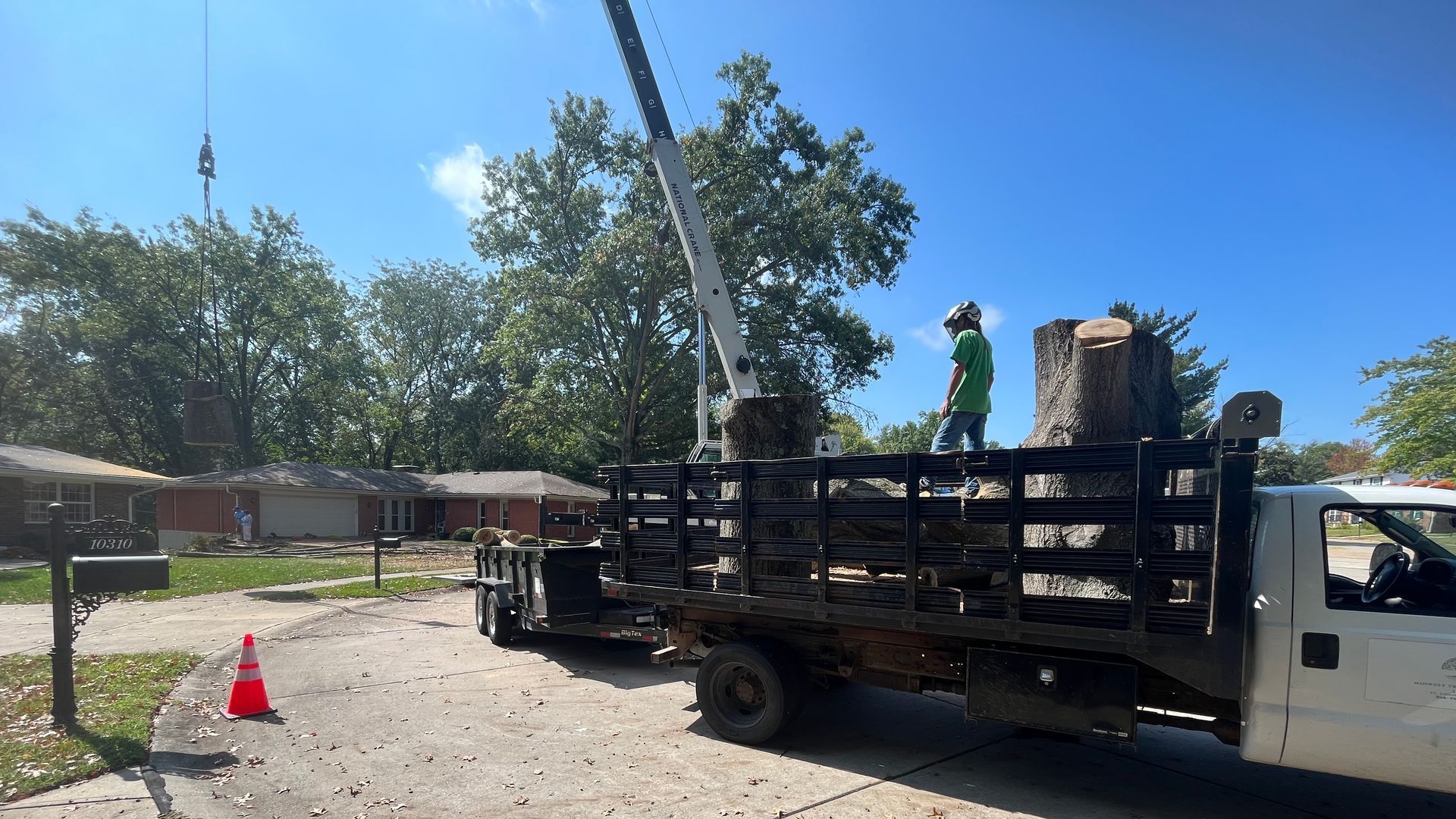A white truck with a crane on the back of it is parked in front of a house.