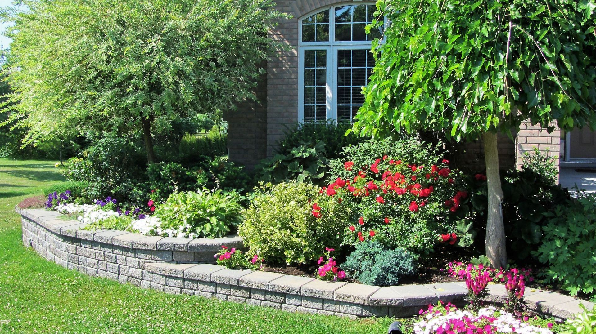 A brick house with a lush green lawn and flowers in front of it.