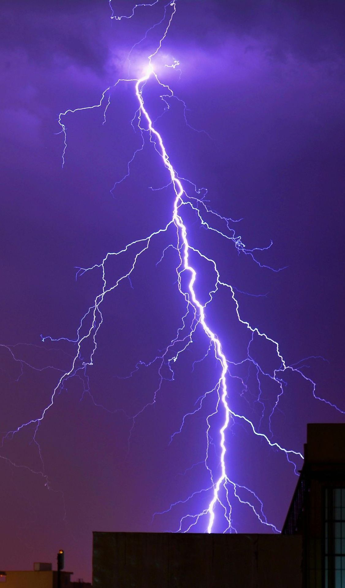 A purple lightning bolt strikes a building at night