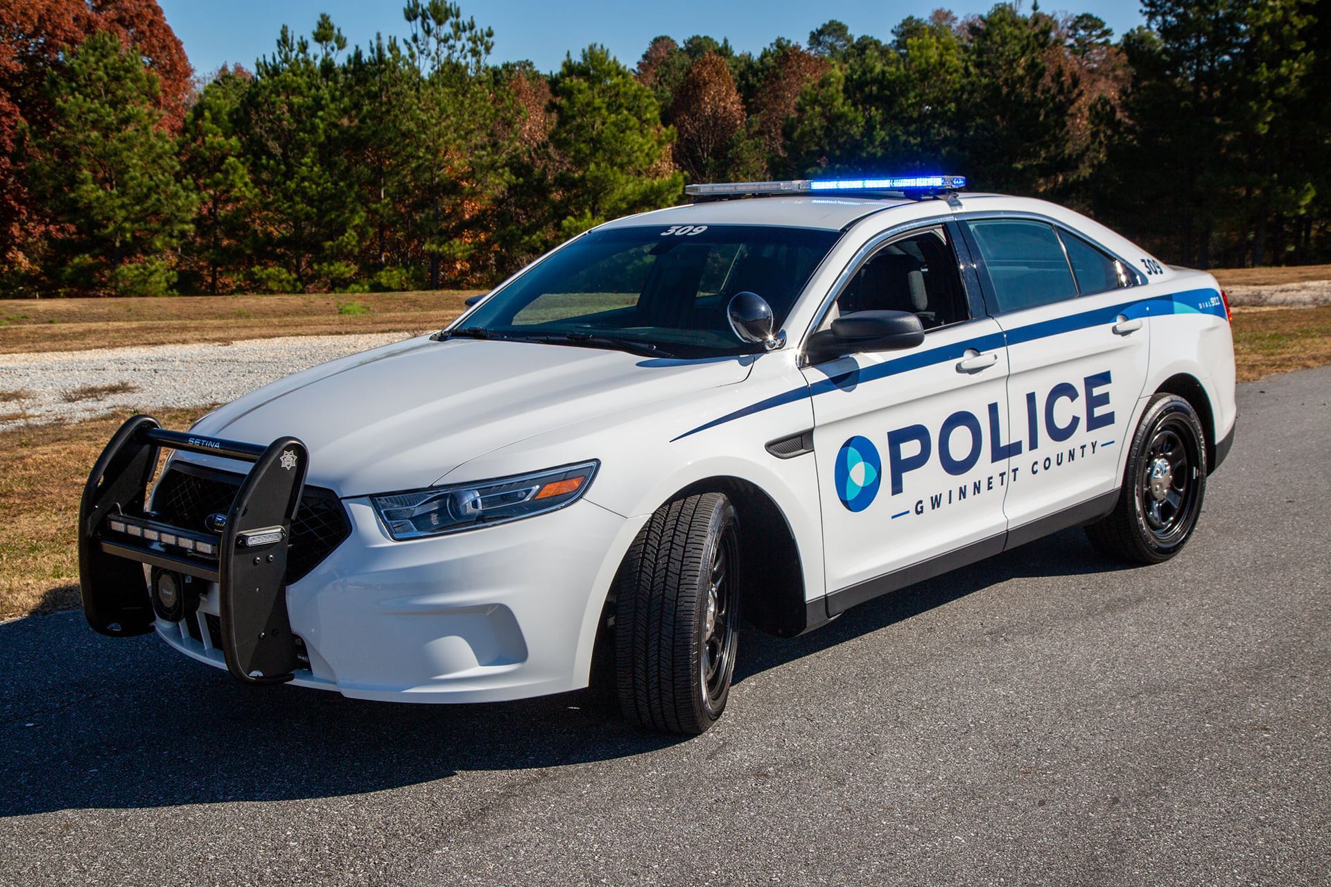 State Trooper patrol car parked on a street; black and gray with logo.