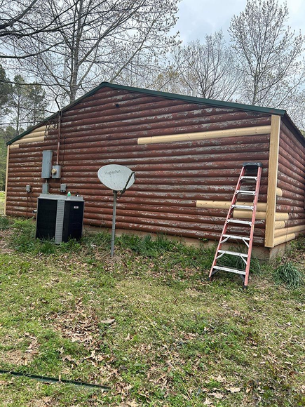 Log cabin with a satellite dish and a ladder outside.