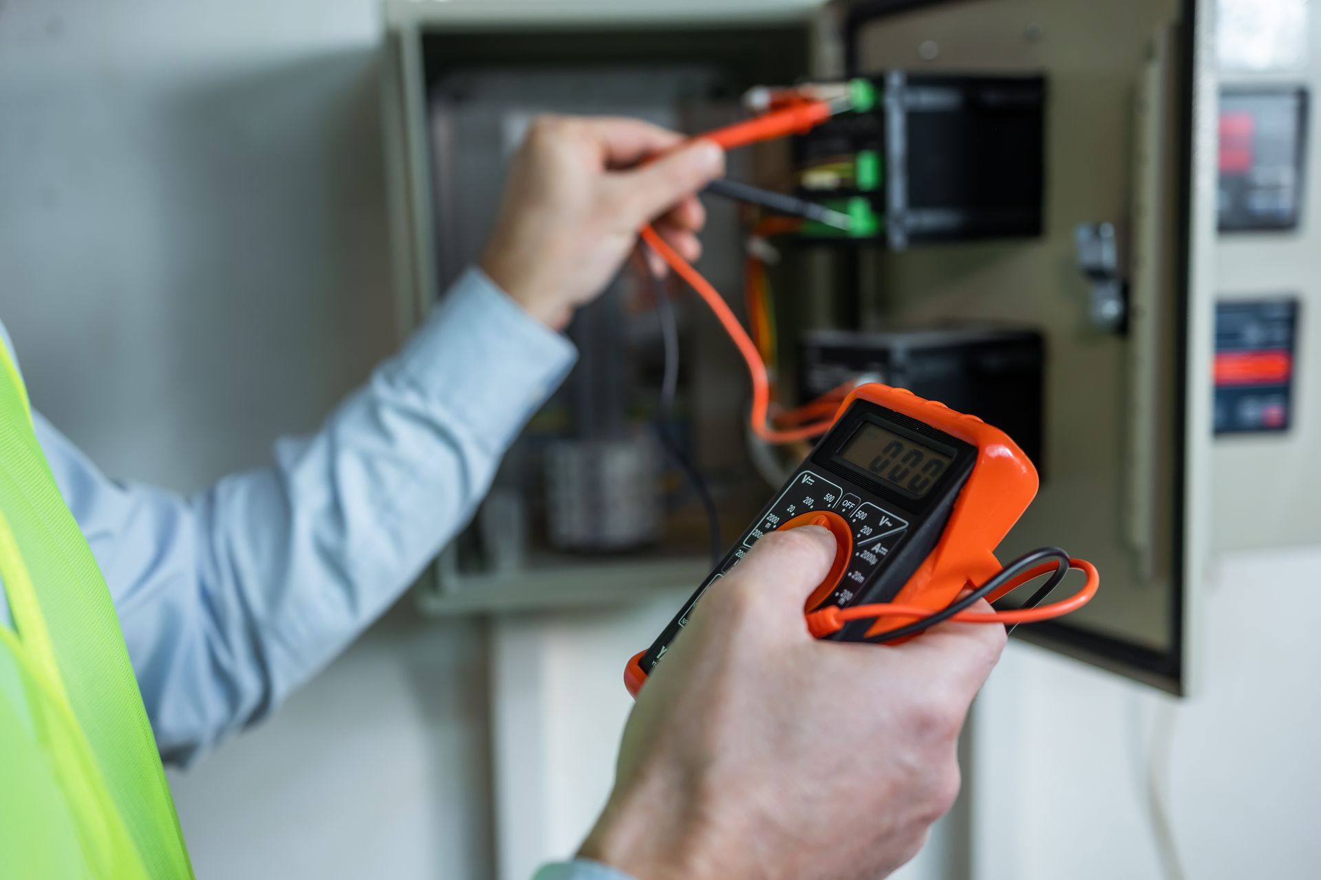 A technician performing electrical troubleshooting with an insulated screwdriver on a control panel.