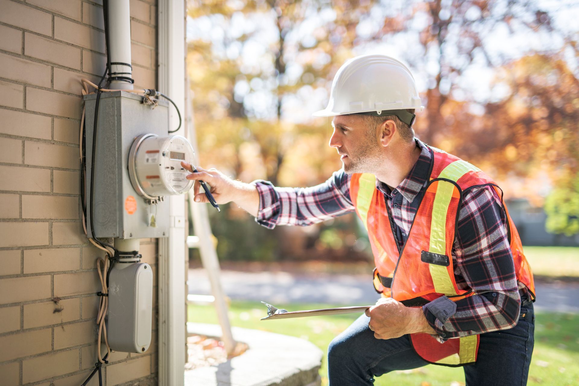 Man with a hard hat inspecting an electric panel.