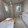 Modern white bathroom with soaking tub, glass shower, vanity, and toilet under bright recessed lights