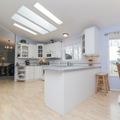 Bright, modern white kitchen with island, skylights, and dining area by sliding glass doors