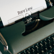 Typewriter with paper labeled “Review” inserted in the carriage.