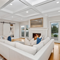 Bright living room with white sectional sofa, fireplace, and large glass doors overlooking trees