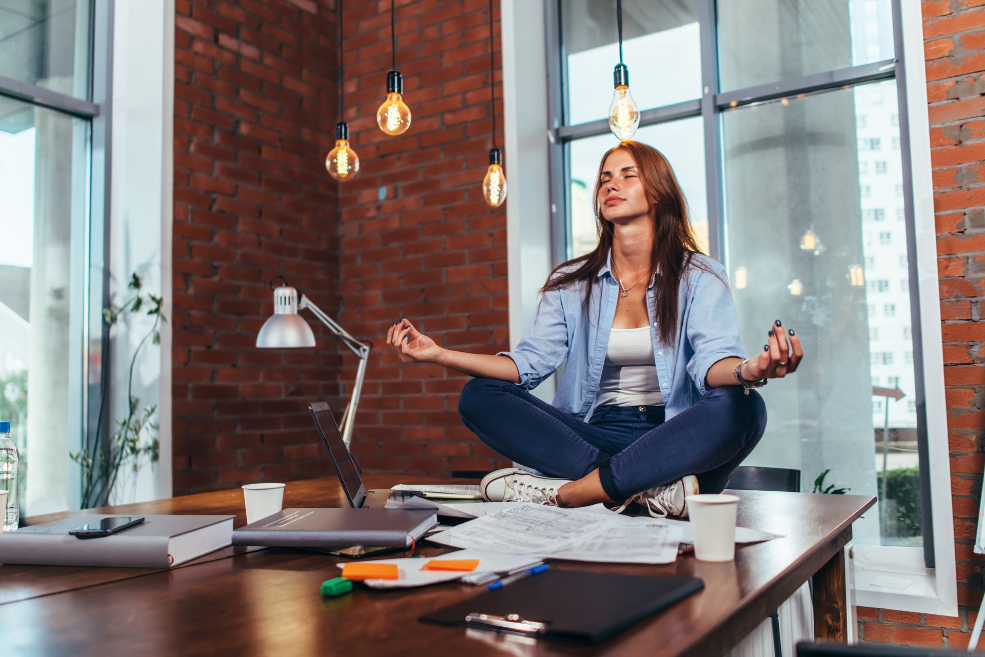 young woman meditating on top of a desk, she is studying levels of emotional intelligence