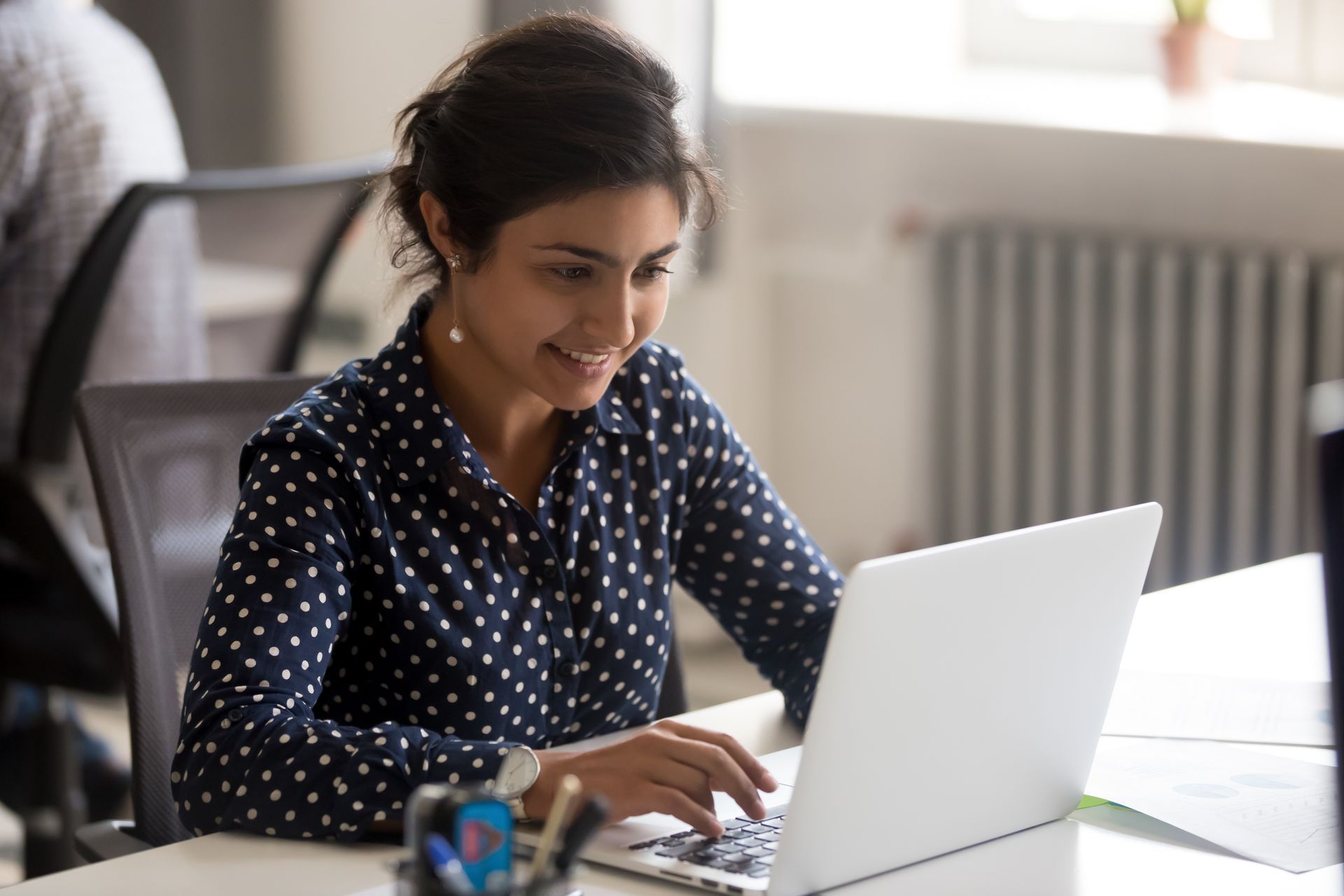 The young Indian American woman searches on her laptop 