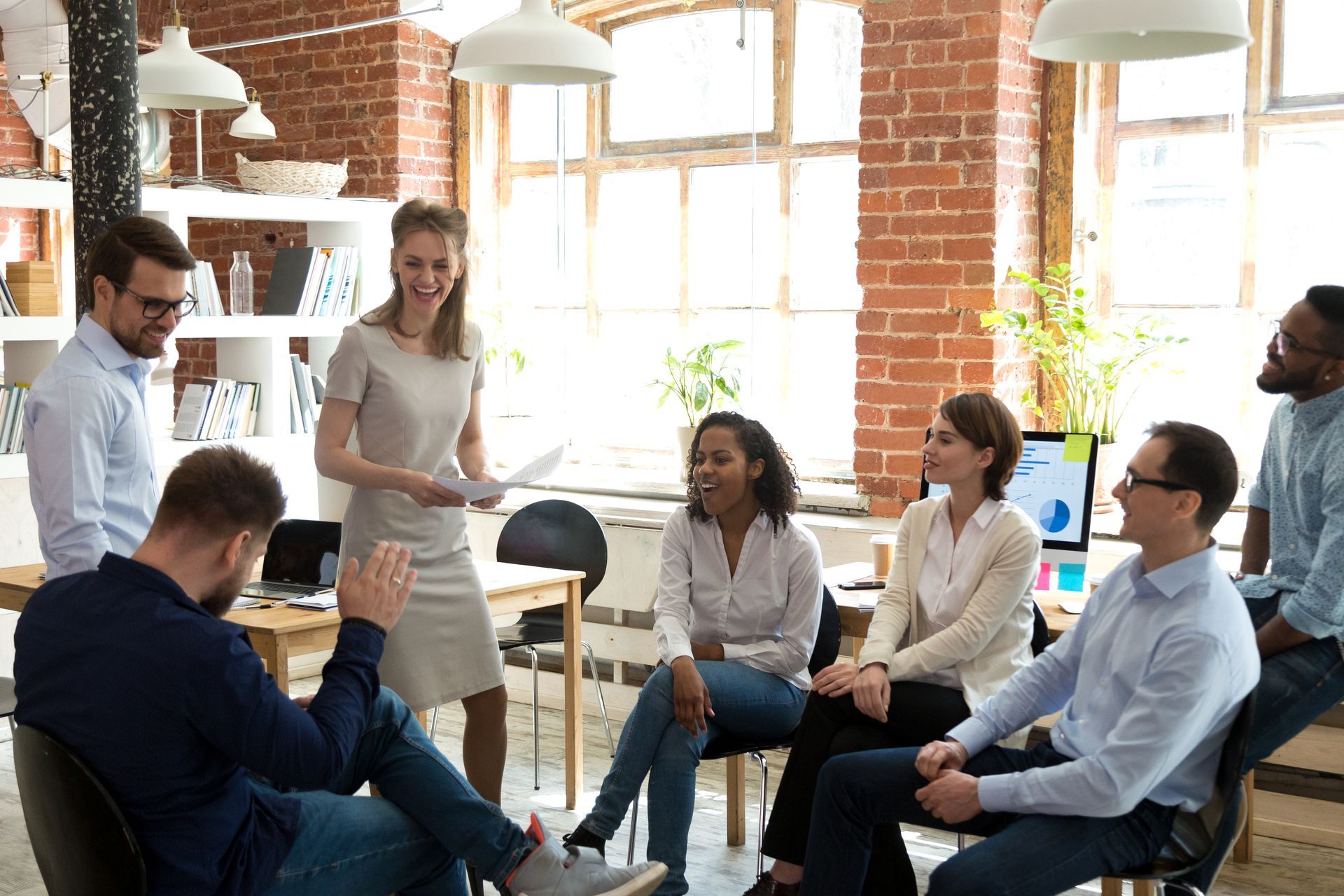 the same woman is now confidently leading a meeting -- she is standing amongst her coworkers who are smiling and excited to get to work -- she has overcome self-doubt and overthinking