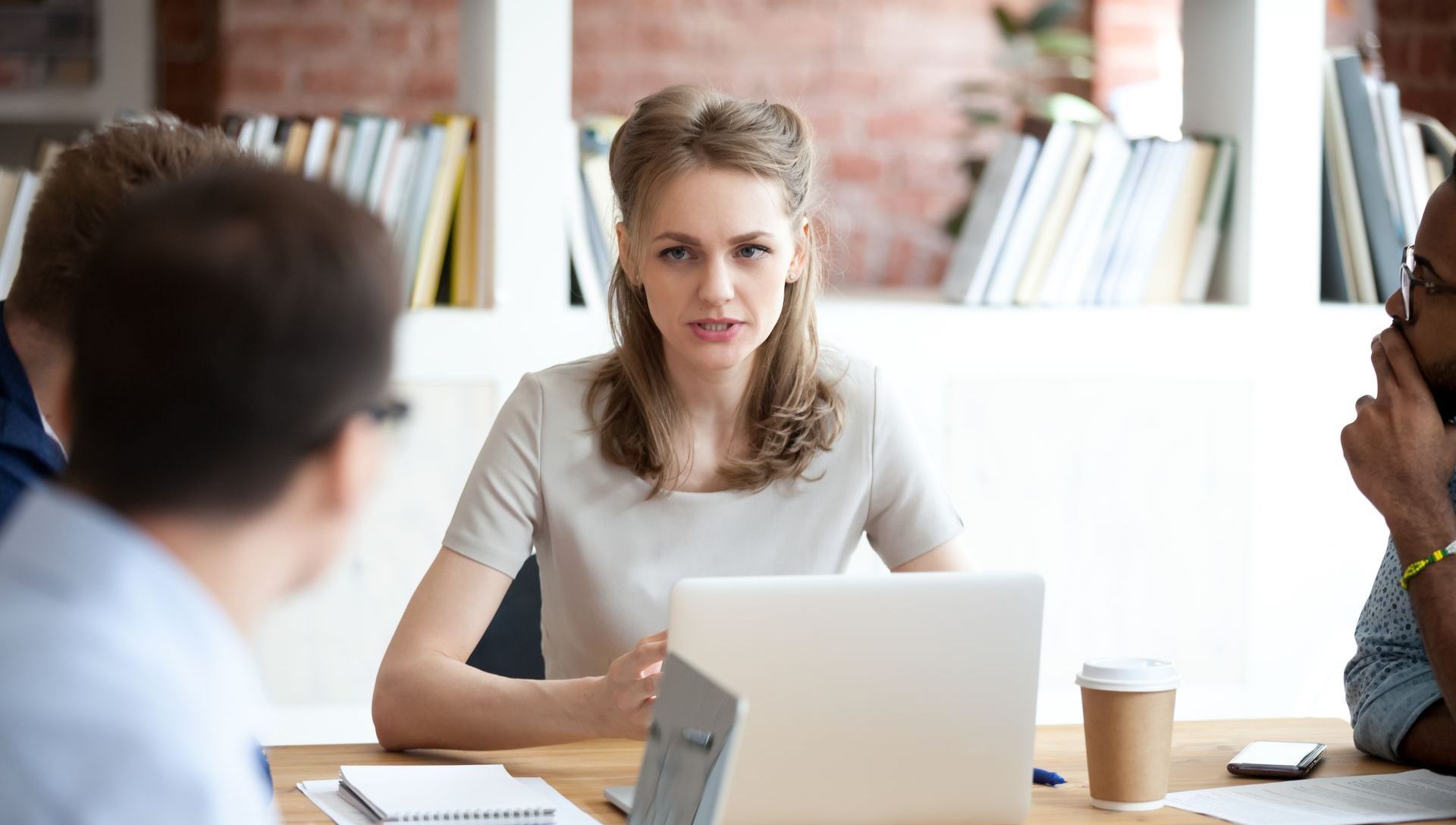 woman leading a meeting, her posture and facial expression show how she has a lot of self-doubt