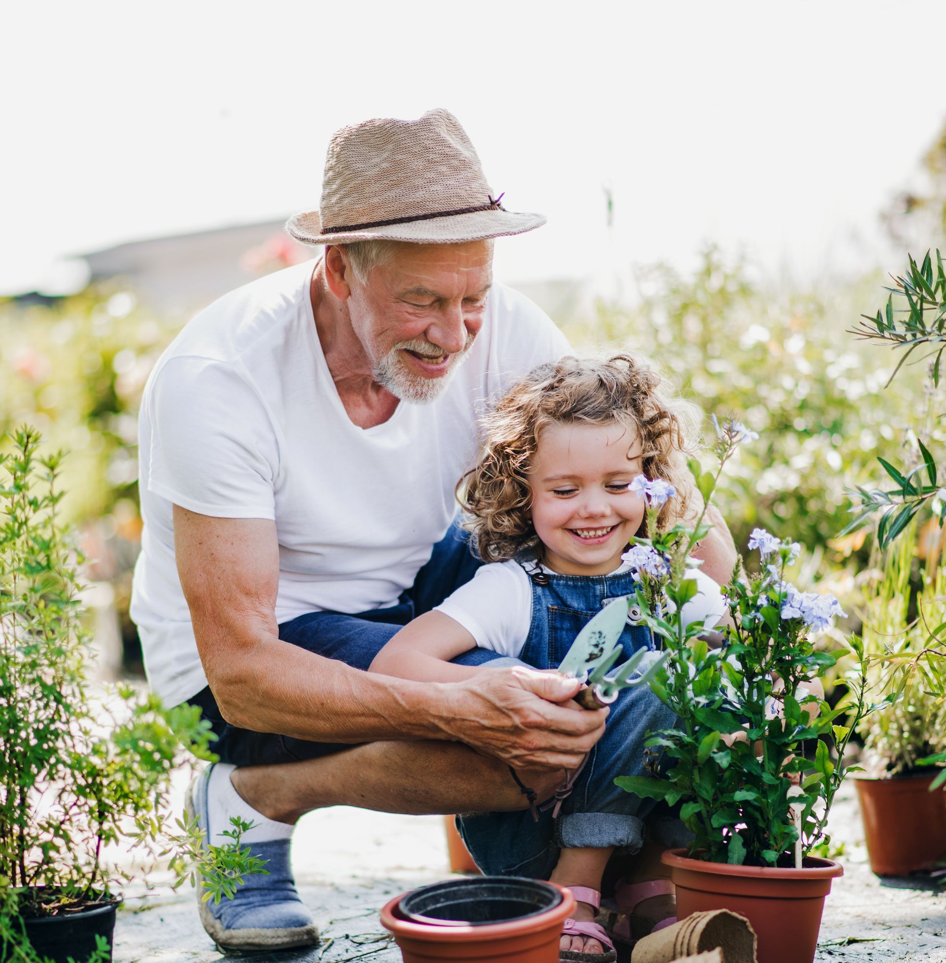 Grandfather gardening with young grandaughter teaching about the importance of smaller steps