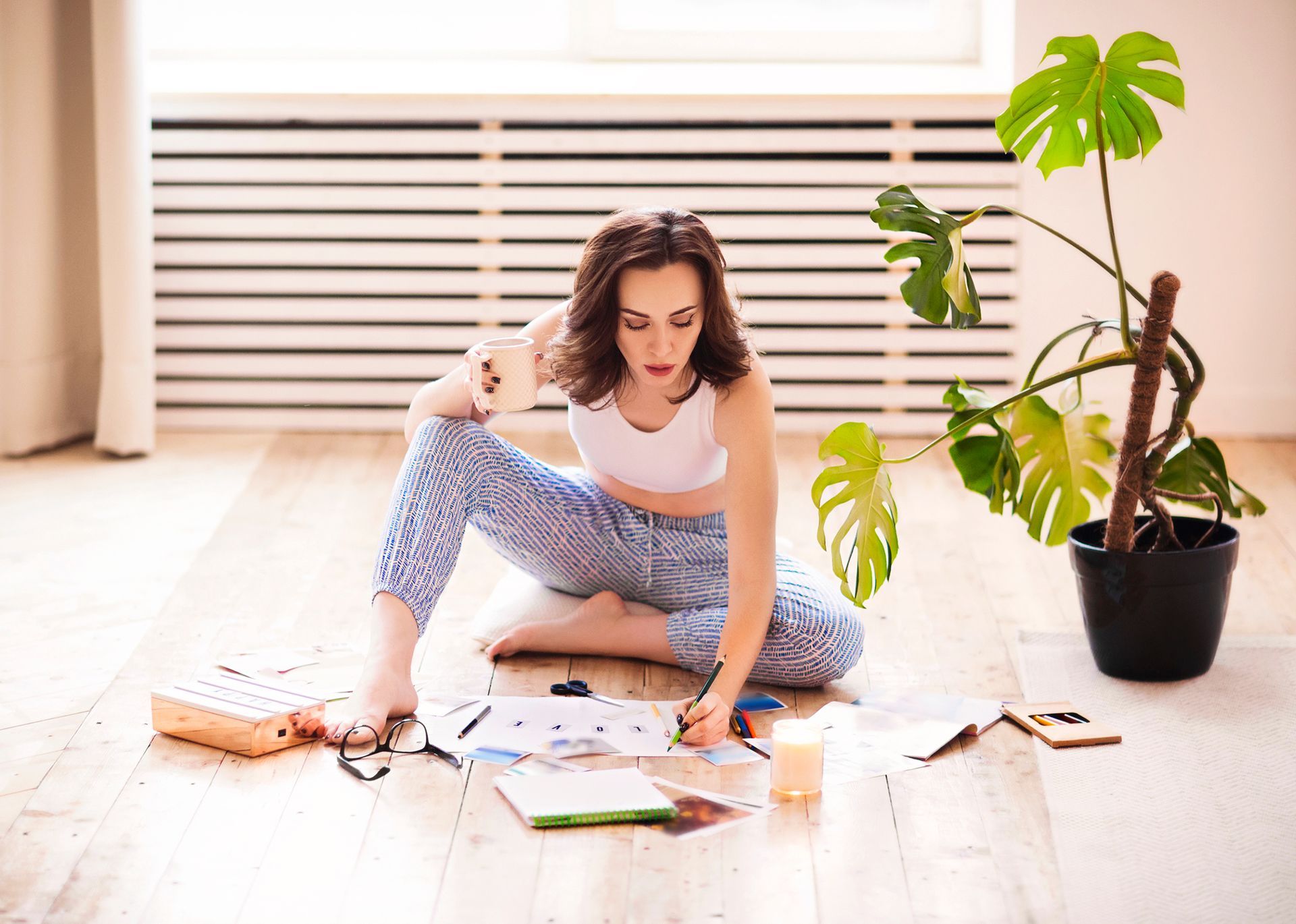 A woman sits on her floor creating a vision board she is learning how to set yourself up for success