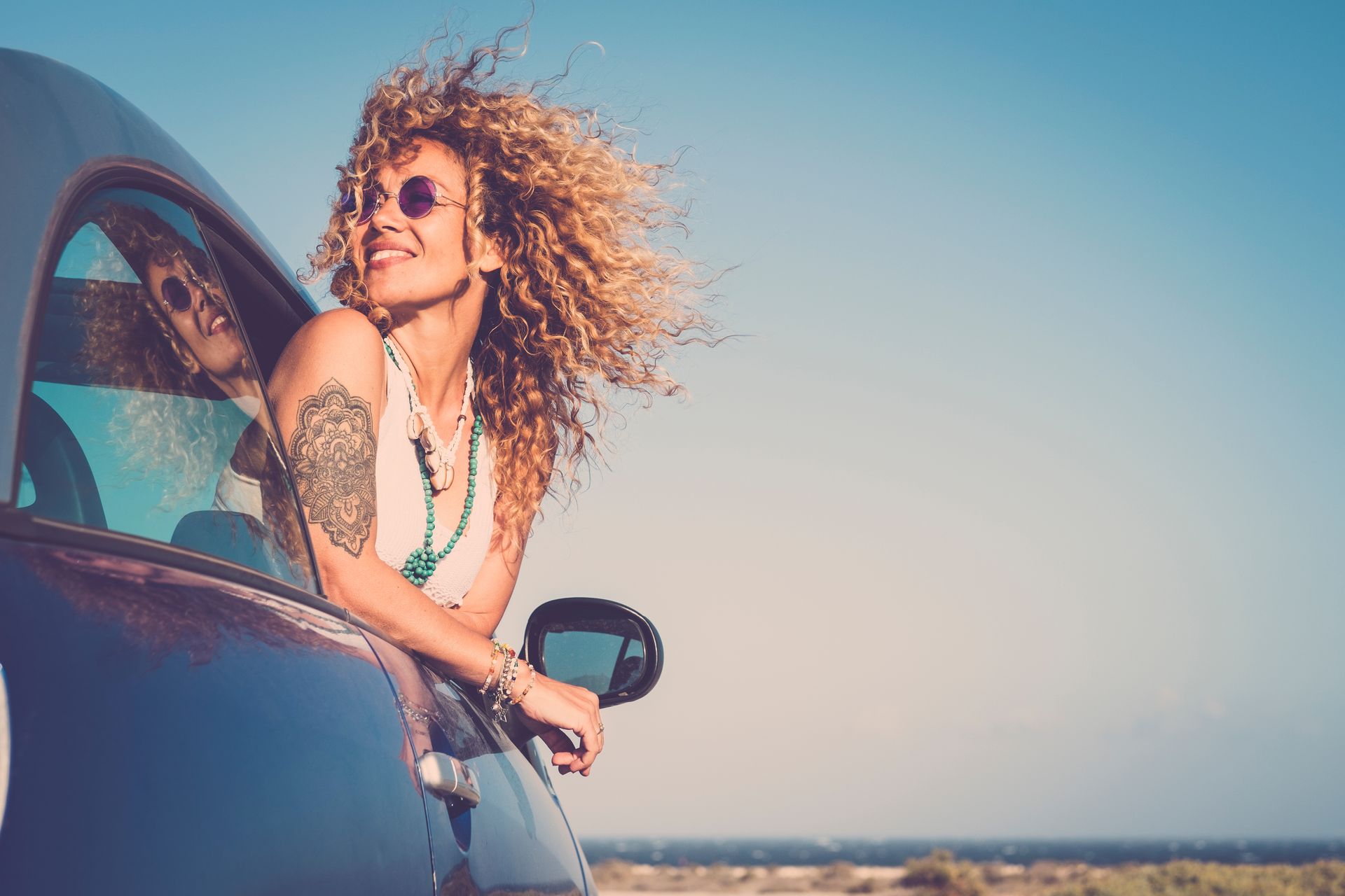 The same woman hangs out of the passenger side, she is smiling and looks back at the road thinking about self confidence vs self esteem