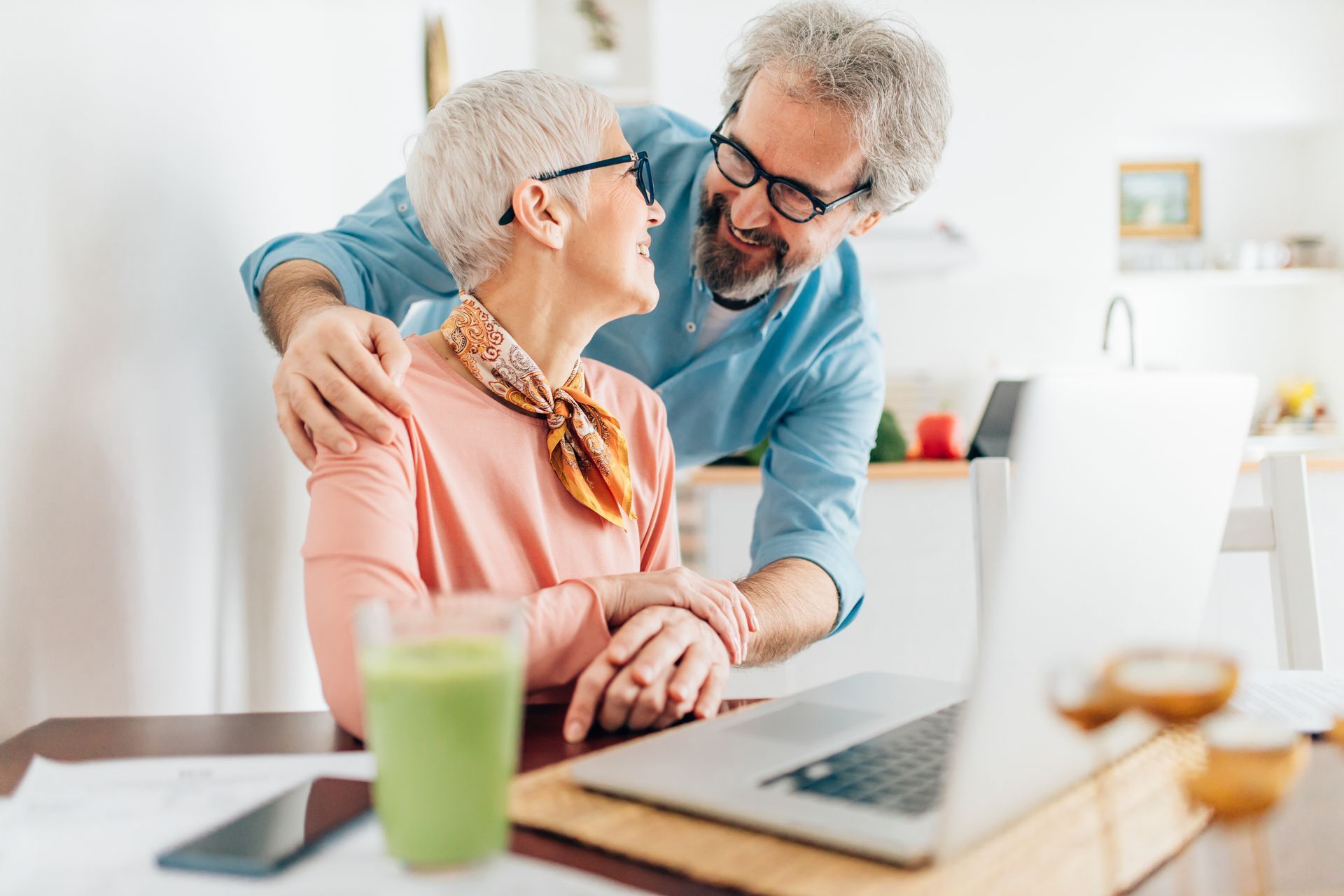 an elderly couple is sitting at a table with a laptop researching the 5 stepping stones in a relationship