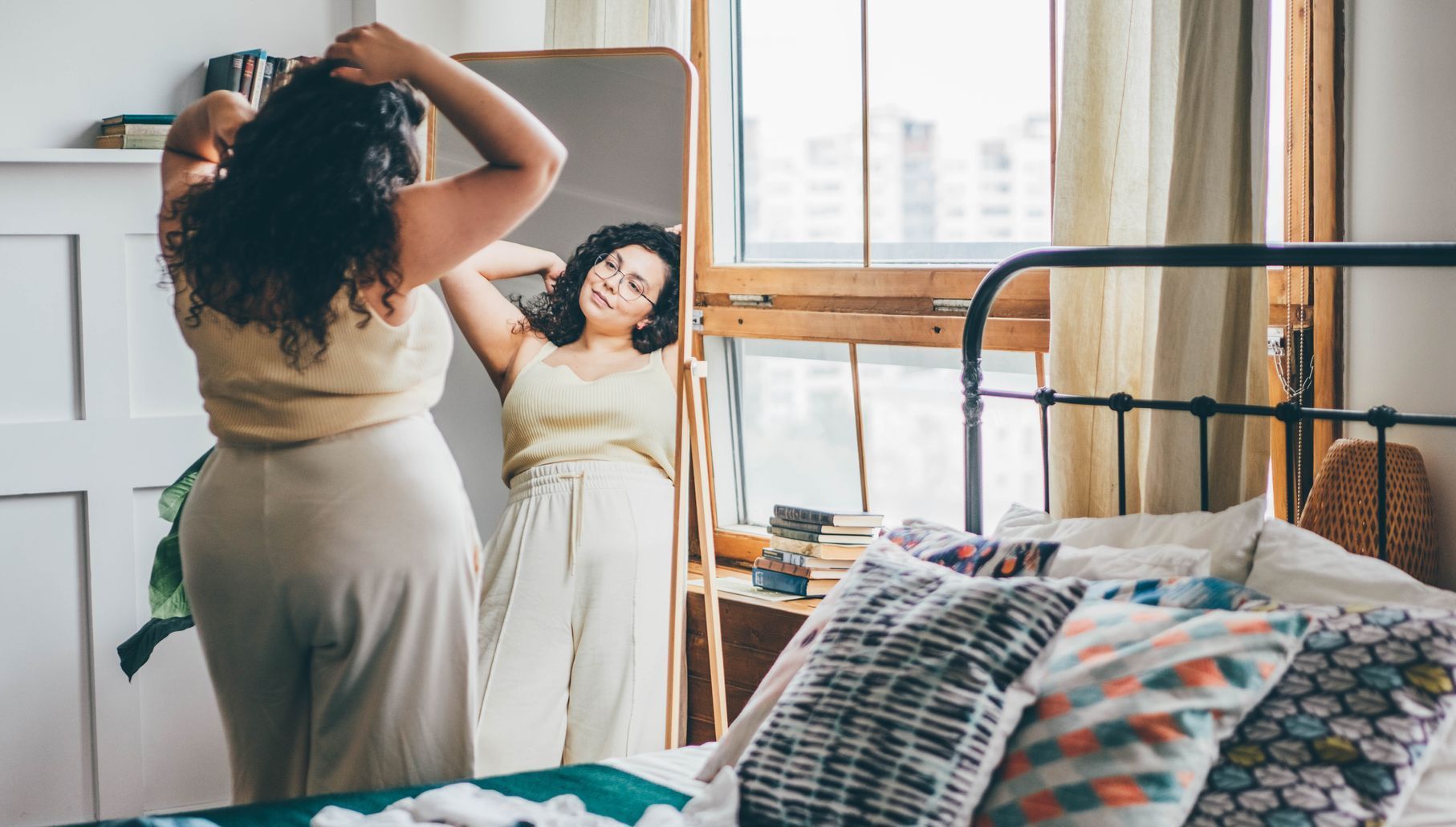 the woman admires her reflection in the mirror, thinking about her progress and how motivation and discipline have guided her journey