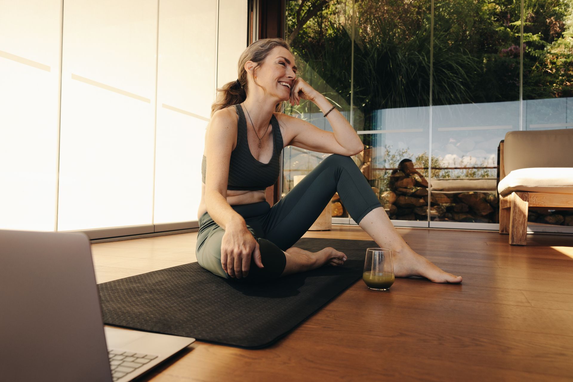 A middle aged woman is doing yoga on the floor, she has a glass of green juice next to her, she knows the benefits of self awareness | benefits of being self aware