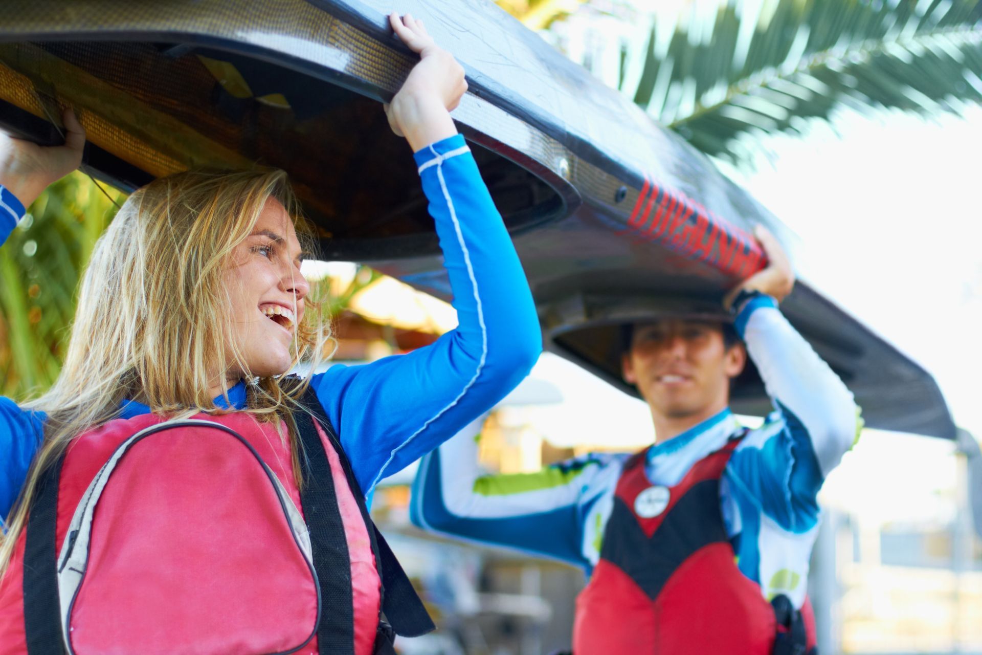 Two friends holding a kyak over their heads, the first person is learning about turning weakness into strength