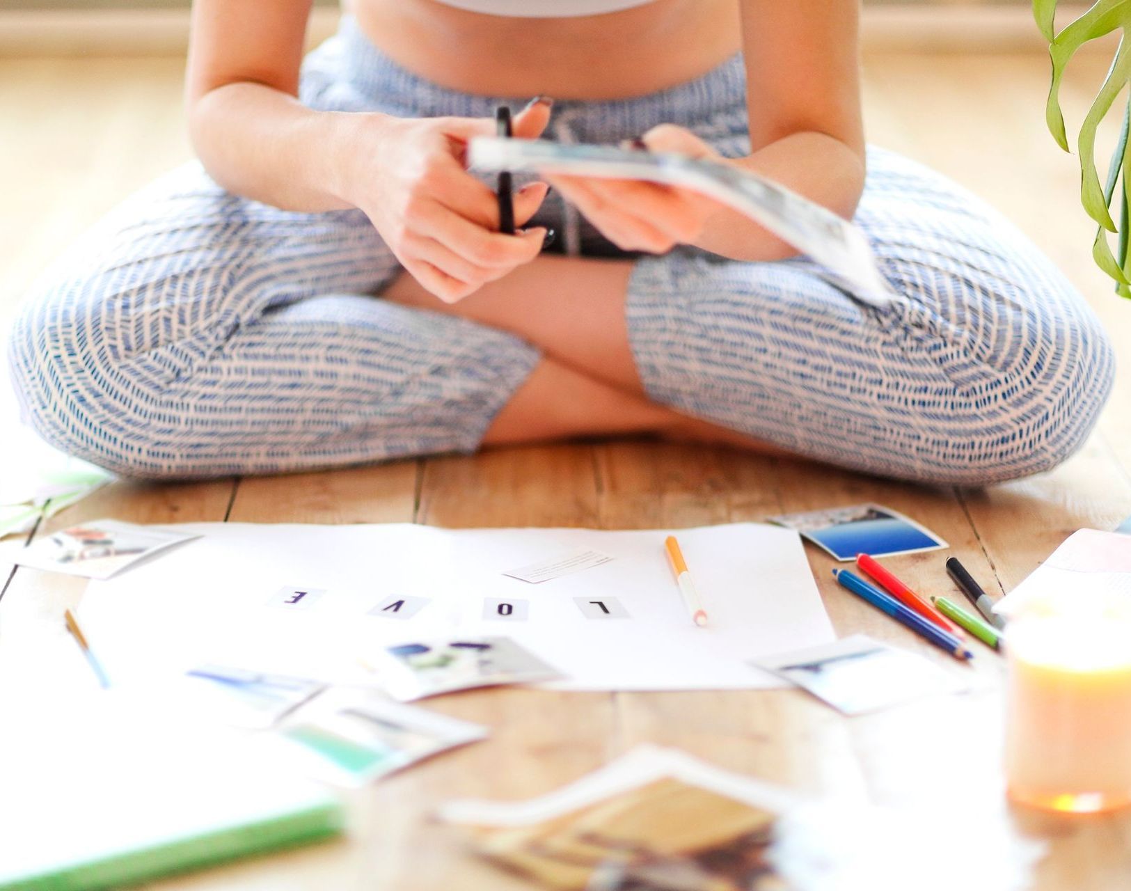 Close up on the woman's torso and vision board on the floor, she is sitting with her legs folded underneath here and she is learning how to set herself up for success