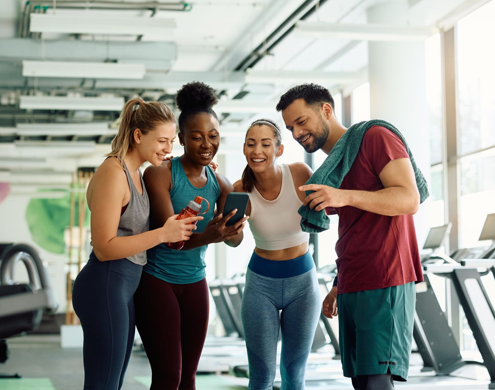 the gym goer and the personal trainer interacting with a group of other gym goers creating more positive influence