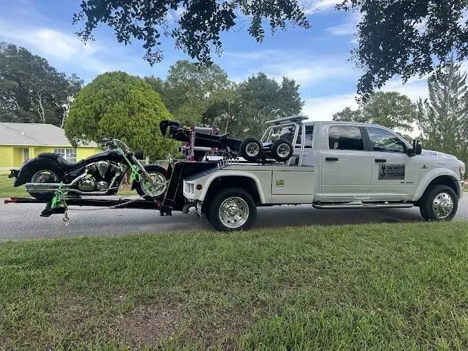 A tow truck is carrying a motorcycle on a trailer.