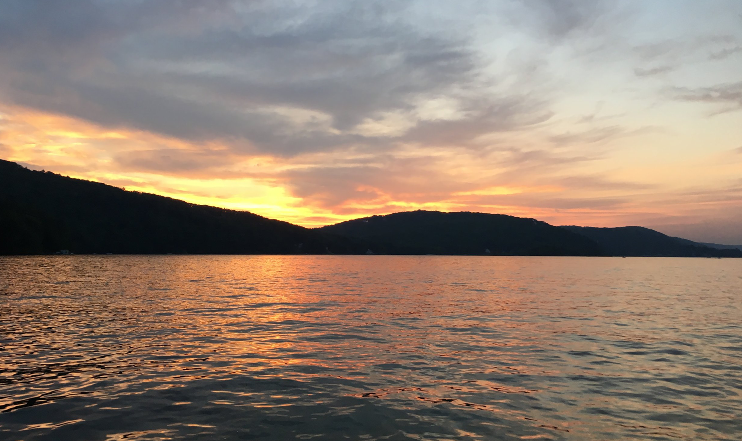 A sunset over a lake with mountains in the background