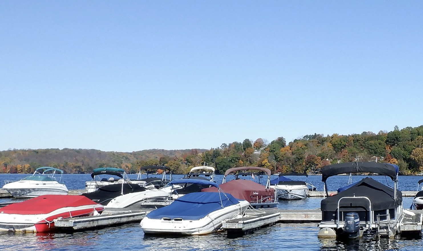 A row of boats are docked at a dock on a lake