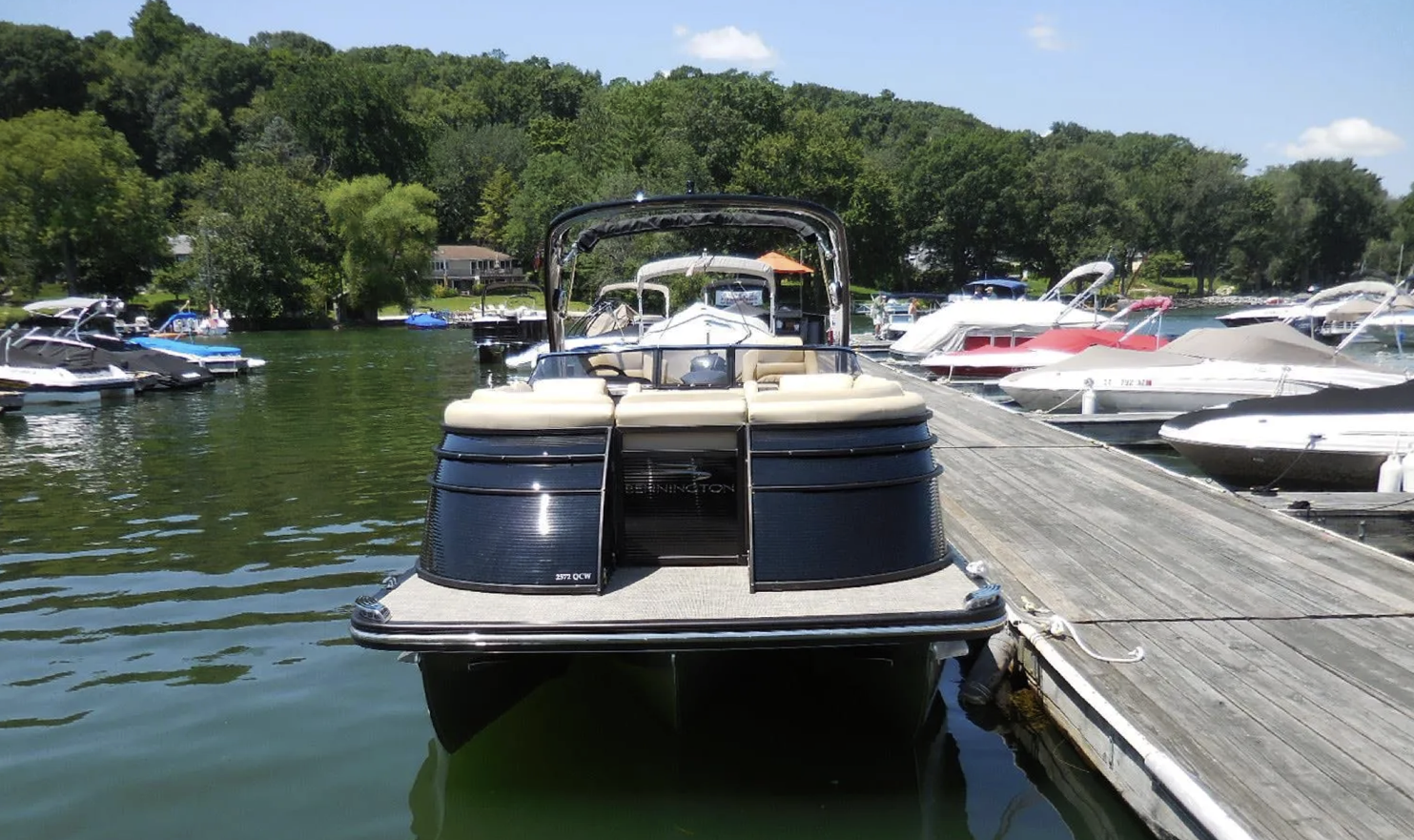 A pontoon boat is docked at a dock on a lake