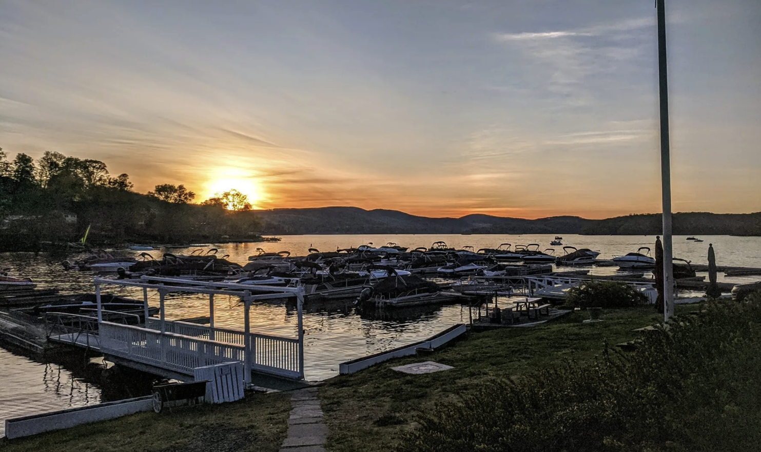A sunset over a lake with boats docked in the water.