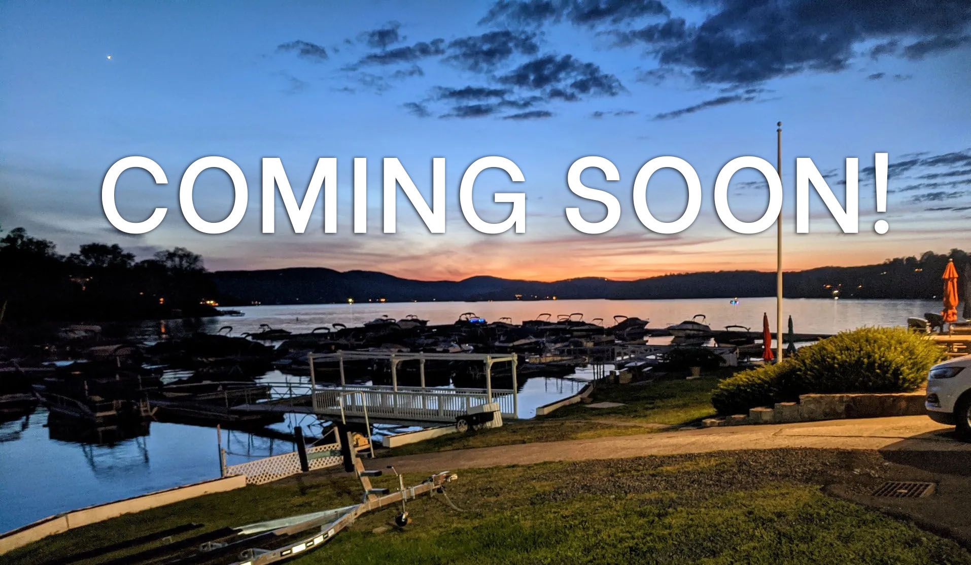 A car is parked on the shore of a lake at sunset.
