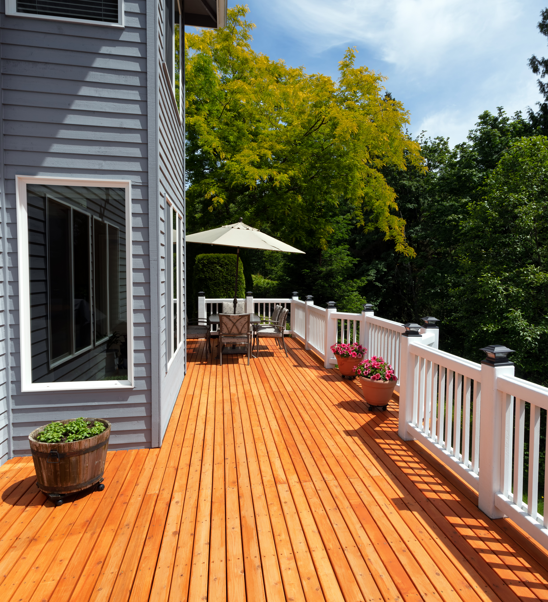 A large wooden deck with a white railing and a white umbrella