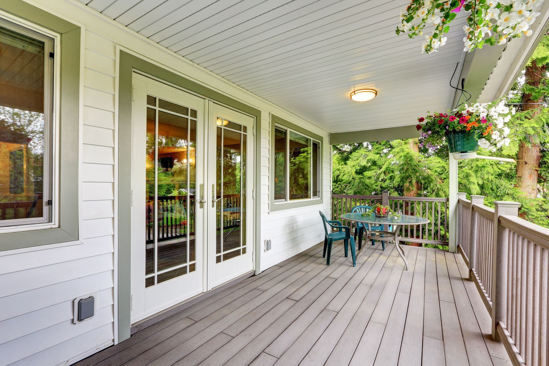 There is a large porch with a table and chairs on it.