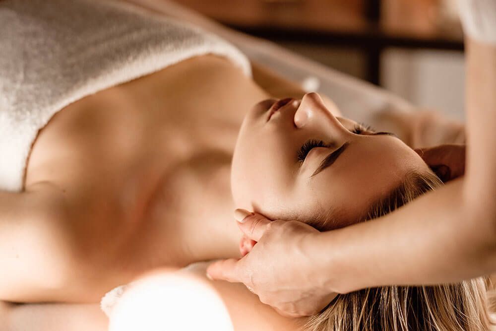 A woman is getting a head massage at a spa.