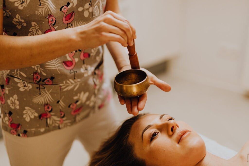 A woman is getting a massage with a bowl on her face.