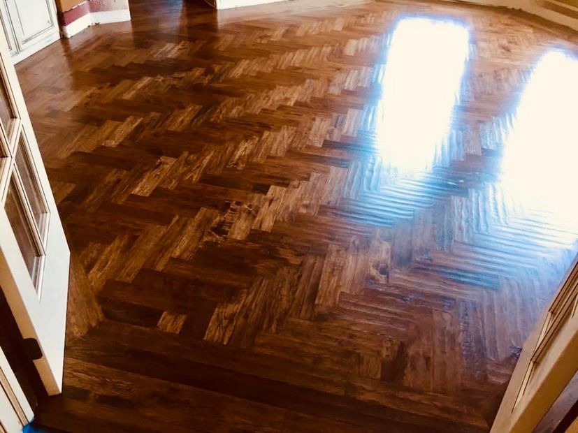 A wooden floor with a herringbone pattern in a room.