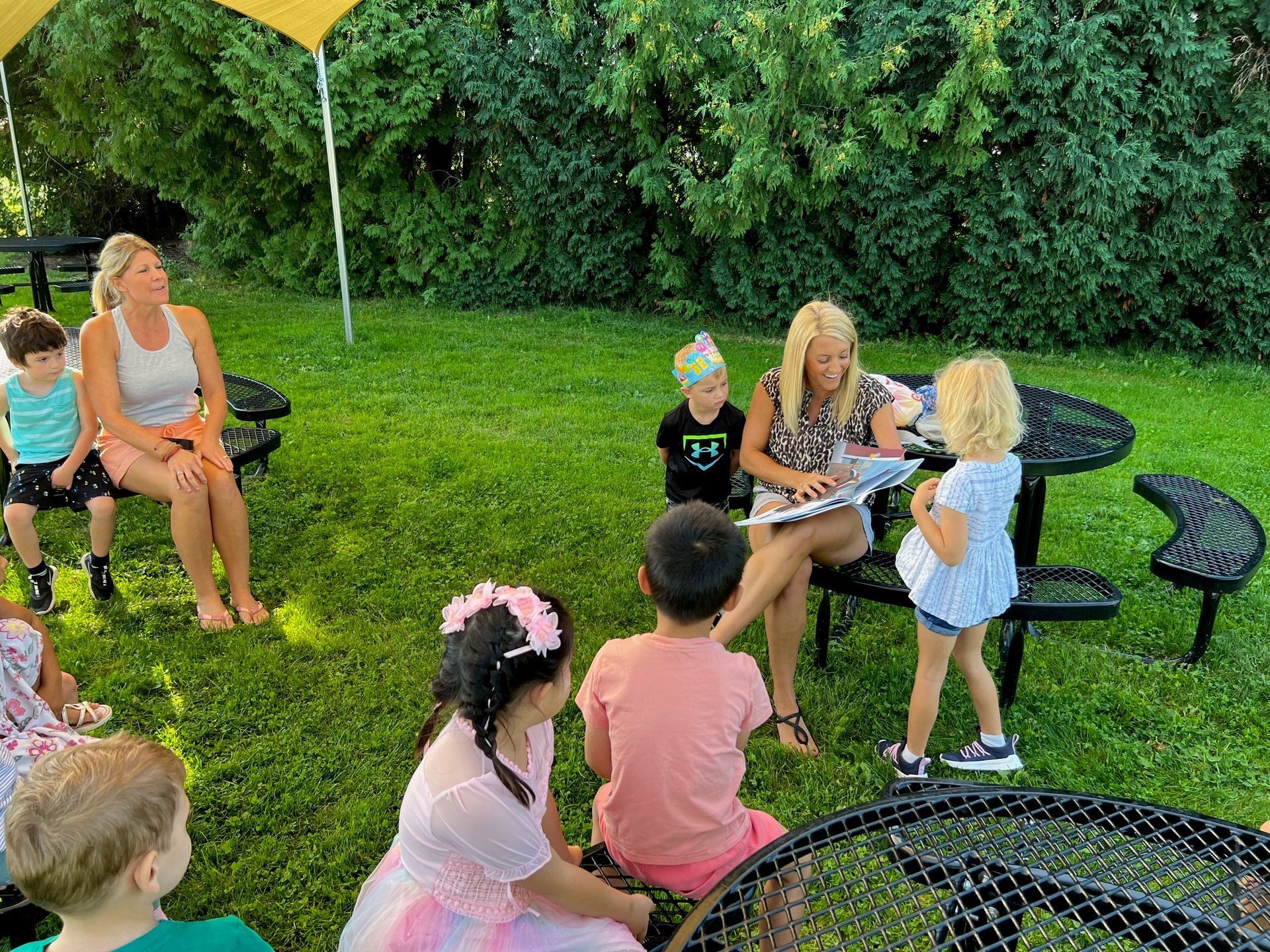 Judy Spencer reading book to Preschool class outside.