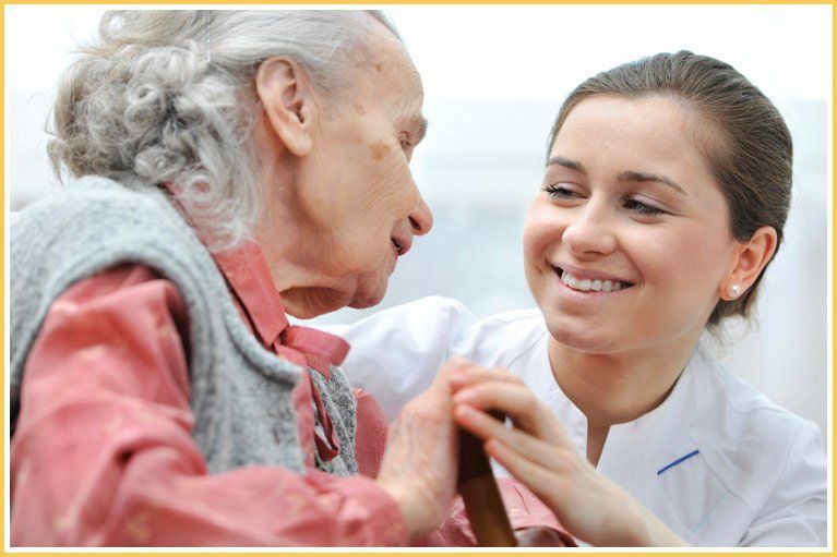A nurse is holding the hand of an elderly woman.