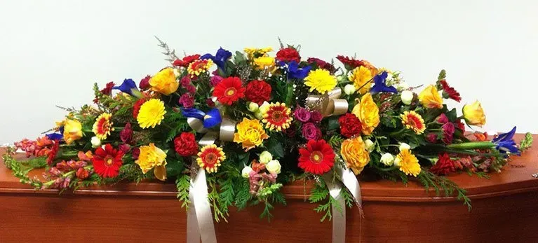 A coffin with a bunch of colorful flowers on it